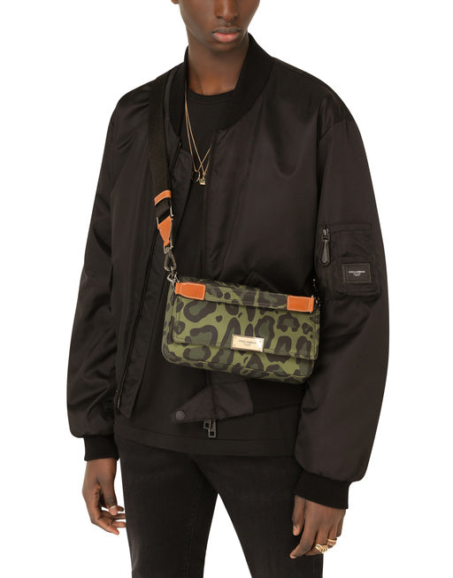 NYLON CROSSBODY BAG WITH LEOPARD PRINT AGAINST A GREEN BACKGROUND AND BRANDED PLATE