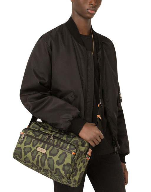 NYLON MESSENGER BAG WITH A LEOPARD PRINT AGAINST A GREEN BACKGROUND AND BRANDED PLATE