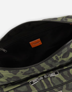 NYLON MESSENGER BAG WITH A LEOPARD PRINT AGAINST A GREEN BACKGROUND AND BRANDED PLATE